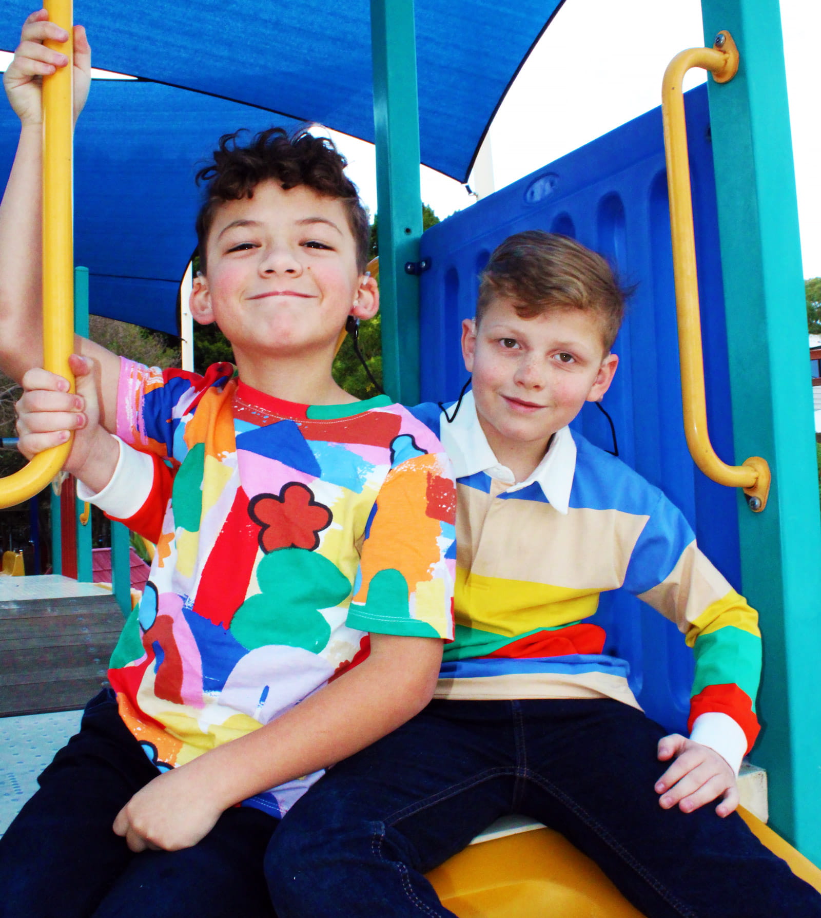 Two kids on a playground wearing loud shirts.